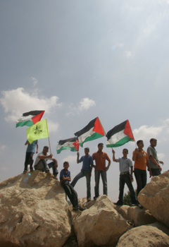 Demonstrators hold Palestinian and Fatah flags in front of Israeli soldiers